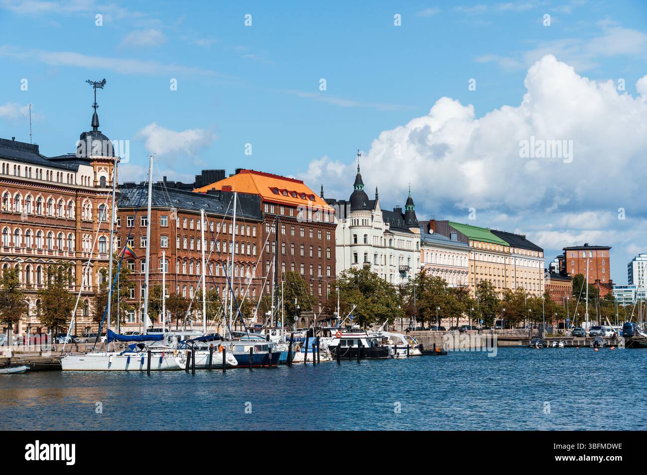Helsinki, Finlandia - 19 agosto 2024: Pittoresca vista sul porto di Helsinki, Finlandia, con edifici colorati e barche a vela sotto un sk parzialmente nuvoloso Foto Stock
