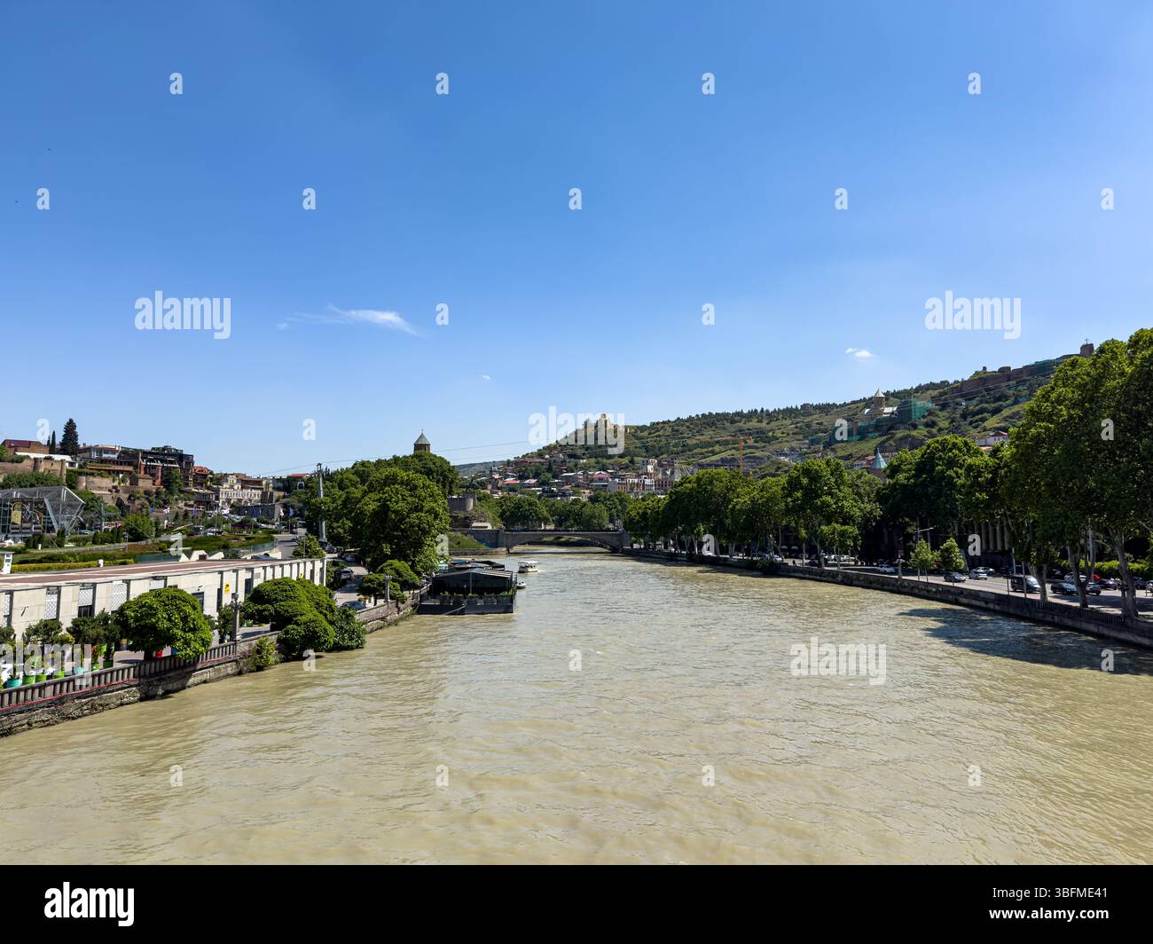Vista del fiume Kura e del paesaggio urbano di Tbilisi dal Peace Bridge in una soleggiata giornata estiva in Georgia. Niente persone. Foto Stock