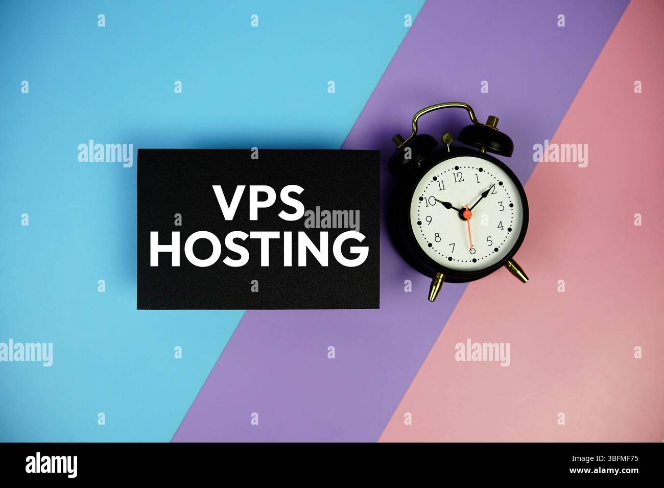VPS Hosting testo con sveglia su carta su sfondo geometrico blu, viola e rosa Foto Stock