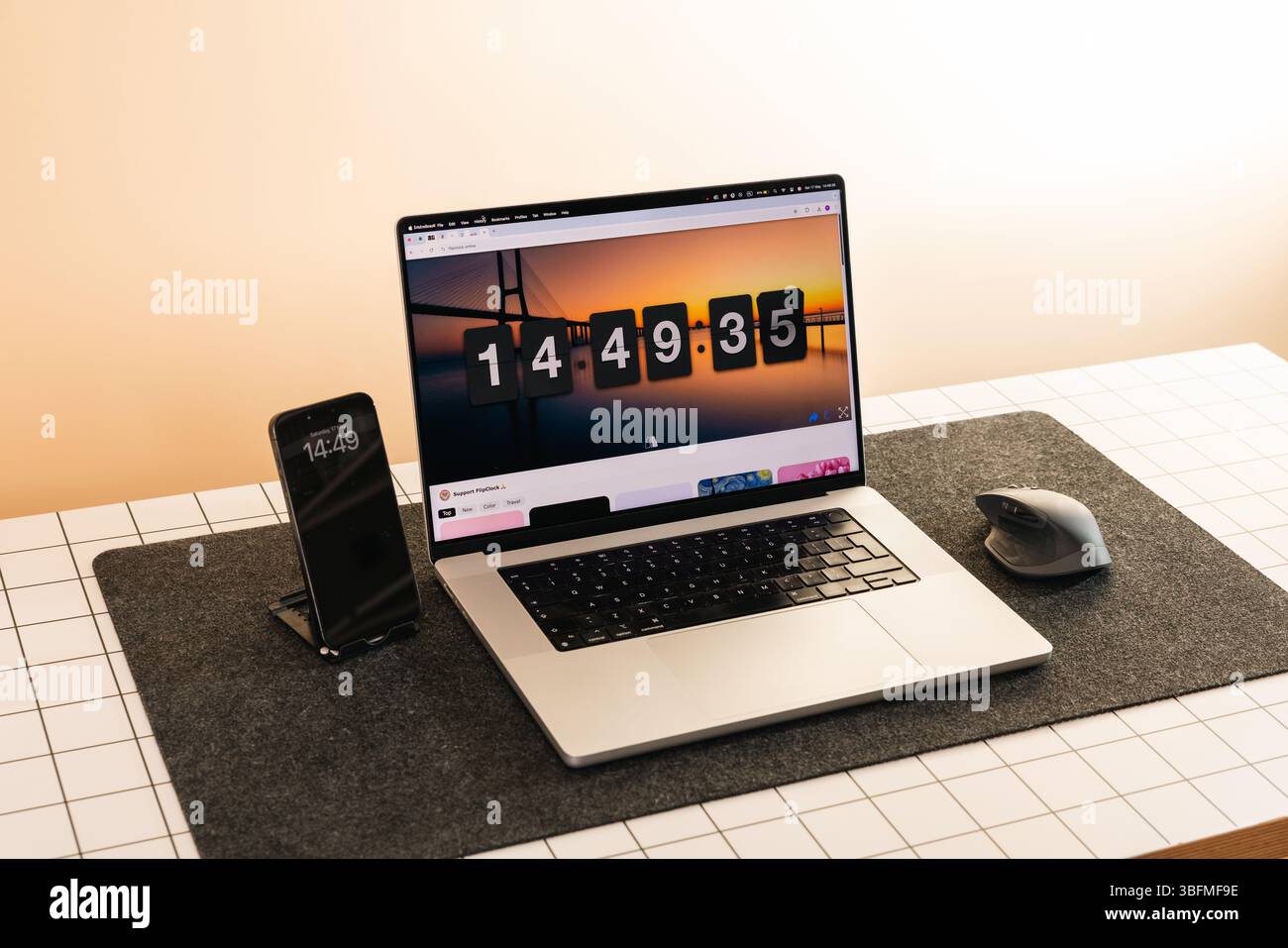 Scrivania pulita e organizzata dotata di un computer portatile con timer per conto alla rovescia su schermo, smartphone e mouse su un tappetino in feltro. Ideale per l'illustrazione di conce Foto Stock