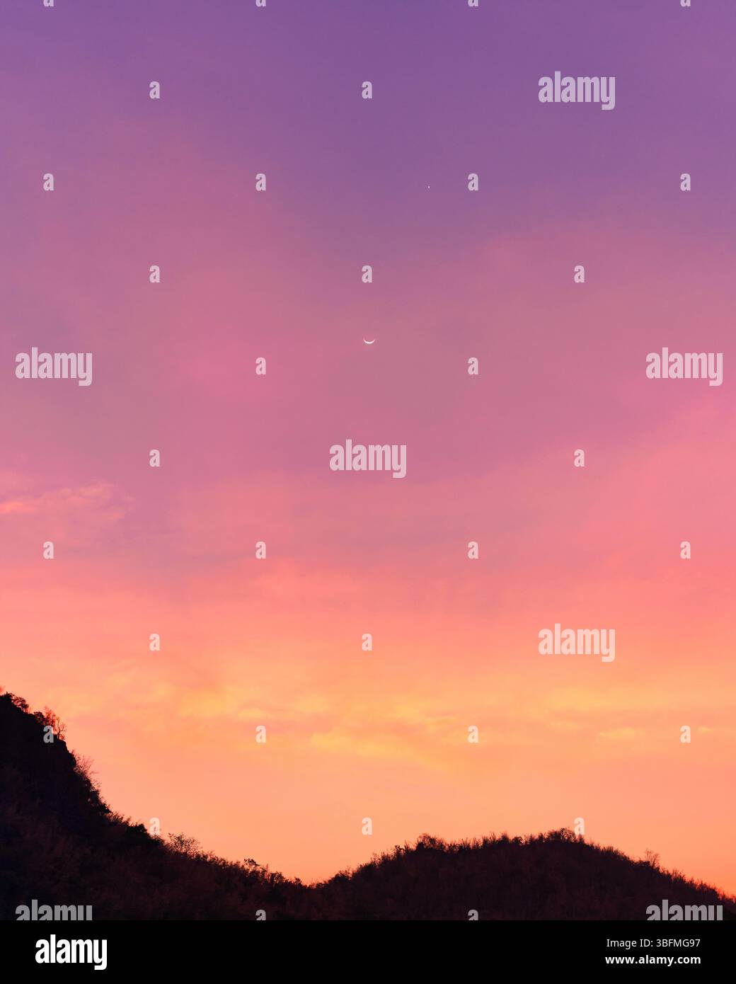 Cielo vivace e colorato con luna crescente e stella sulla montagna sagomata al tramonto Foto Stock