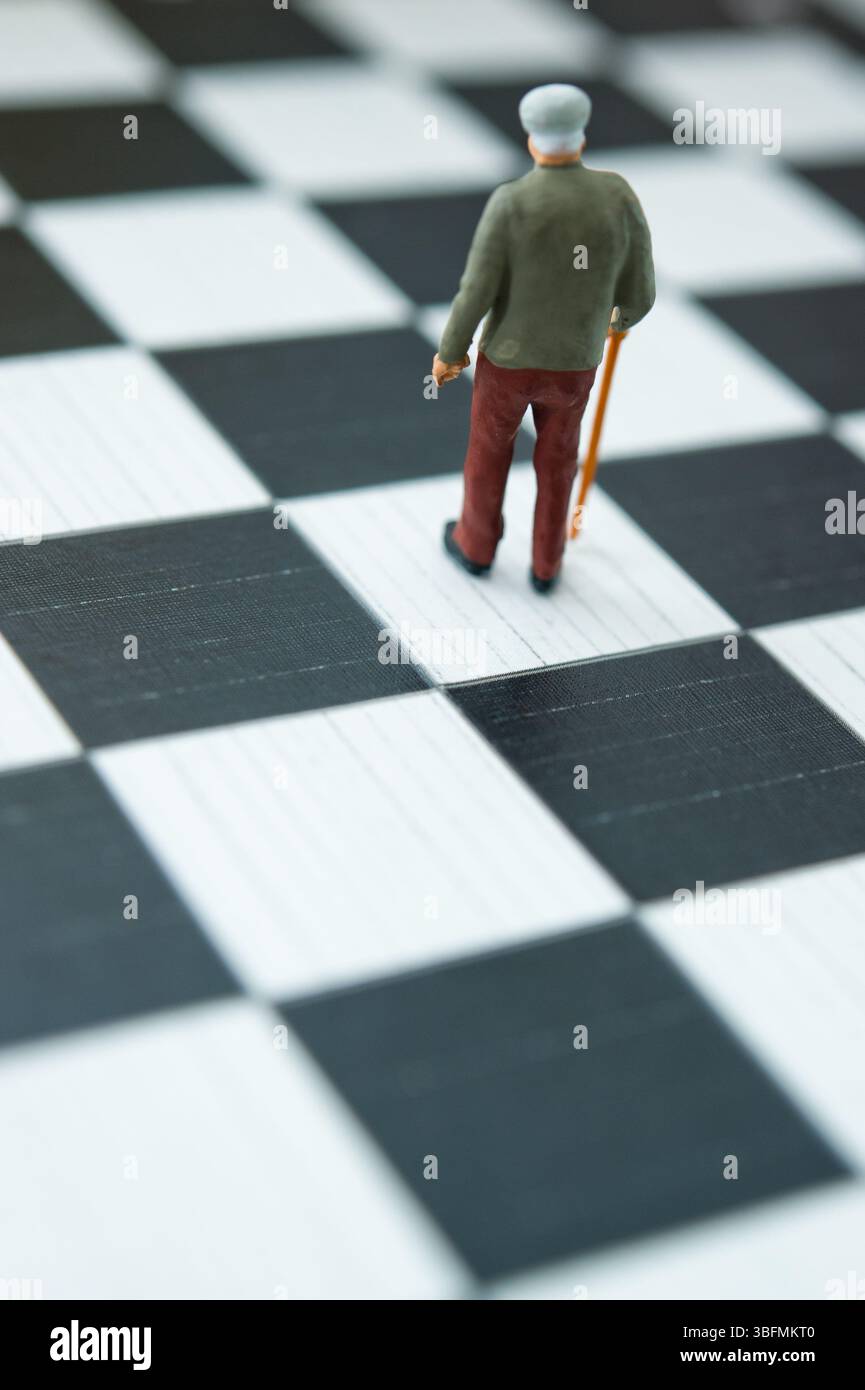 figurine in miniatura di un vecchio uomo con canna su scacchiera, invecchiamento e concetto di vecchiaia Foto Stock