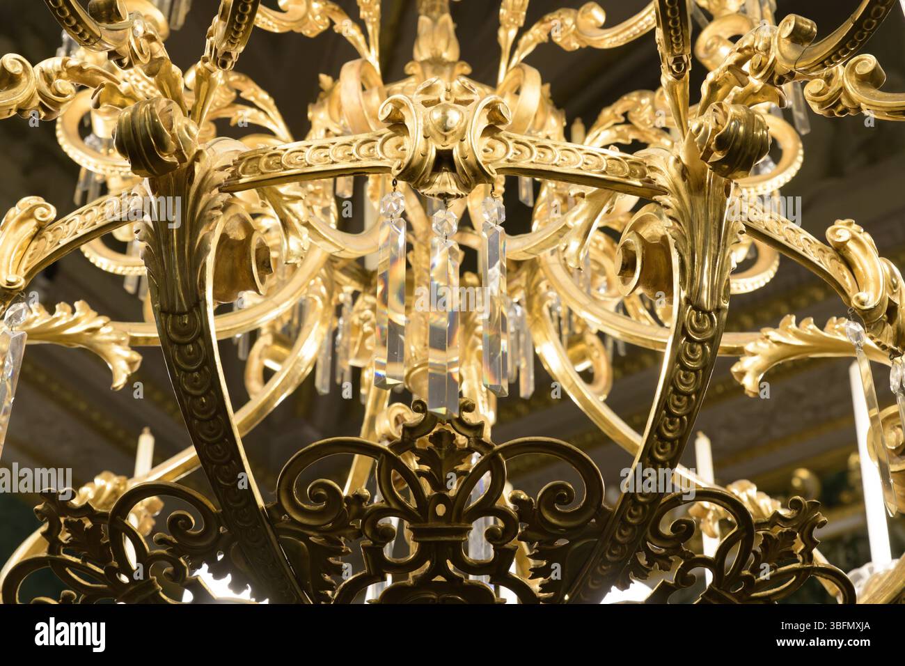 Primo piano di un lampadario dorato decorato con prismi di cristallo e scrollwork in stile rococò a Palazzo Pitti, Firenze, Italia. Foto Stock