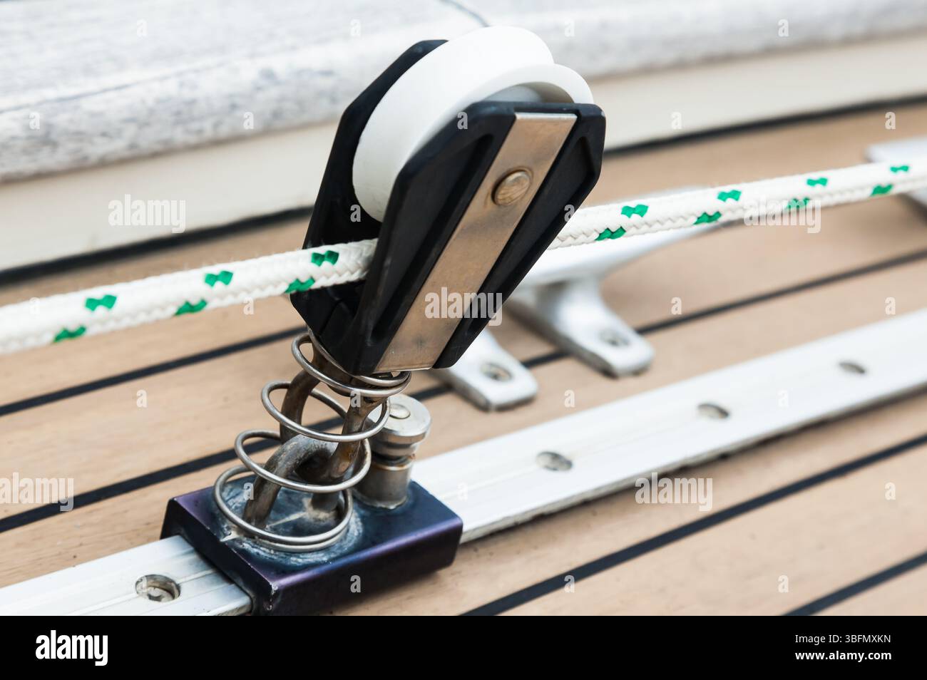 Parte del ponte in teak di uno yacht a vela con elementi di fissaggio per il fissaggio delle funi. Foto Stock