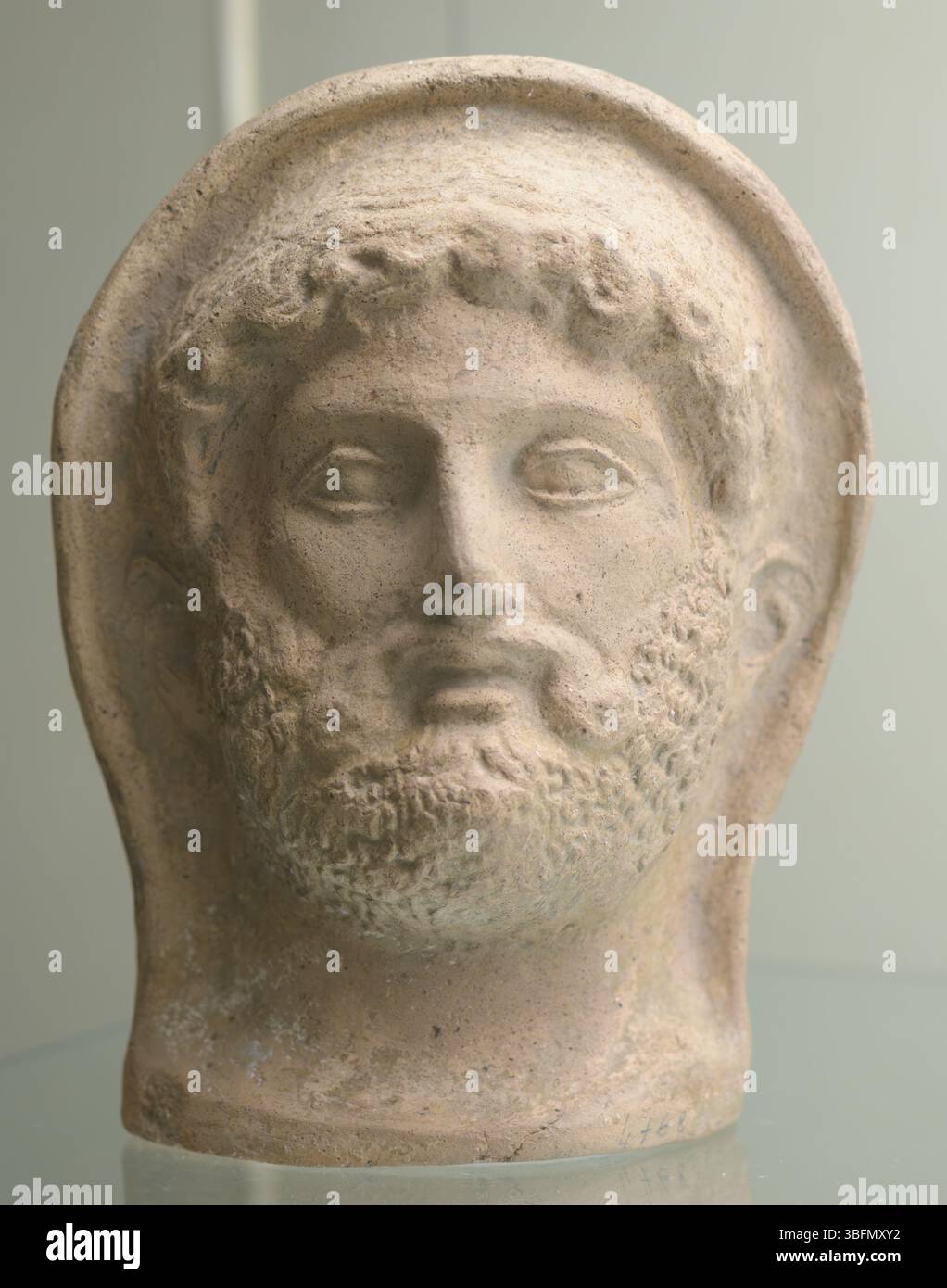 Terracotta ex voto con testa barbuta maschile di antica collezione, realizzata in Italia nel IV-III secolo a.C., ritratto frontale. Foto Stock