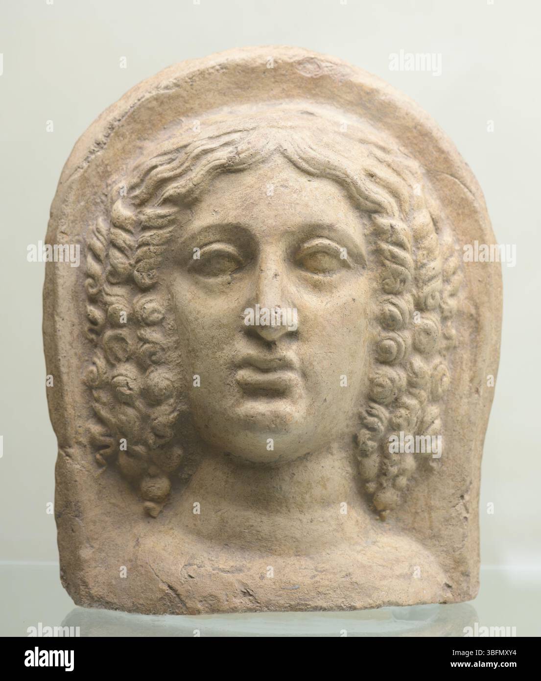 Terracotta ex voto con testa femminile, capelli ricci, elementi morbidi, di antica collezione, datata al IV-III secolo a.C., probabilmente proveniente dall'Italia centrale. Foto Stock