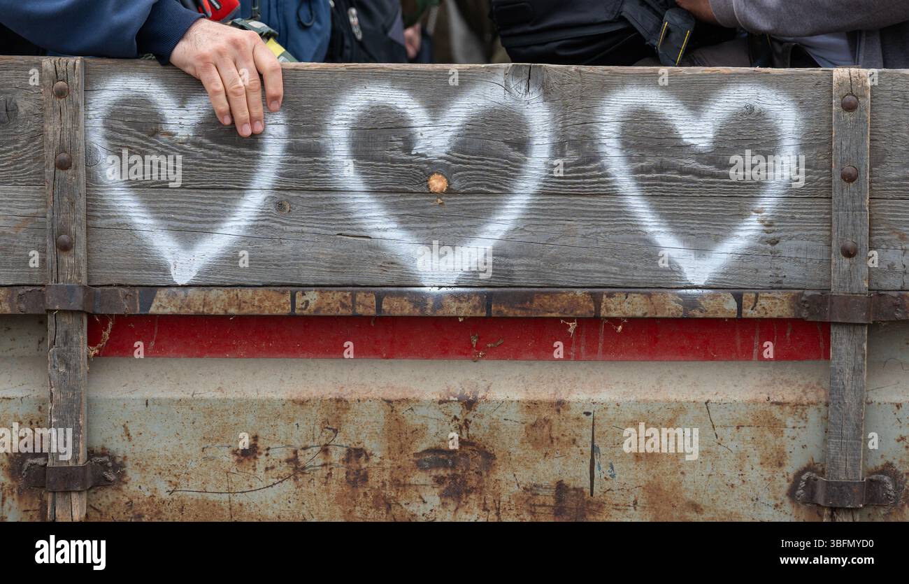 Tre cuori bianchi e una mano umana su un rimorchio per trattori in legno. Primo piano, prospettiva. Tocca l'amore. Concetto Foto Stock