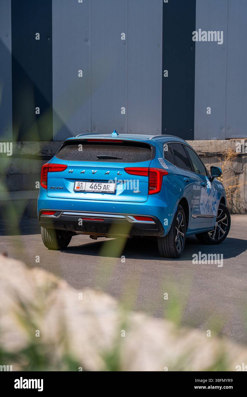 Bishkek, Kirghizistan - 12 ottobre 2024: Vista dall'angolo posteriore di un SUV 4WD Haval Jolion blu parcheggiato con una vista parziale delle rocce in primo piano Foto Stock
