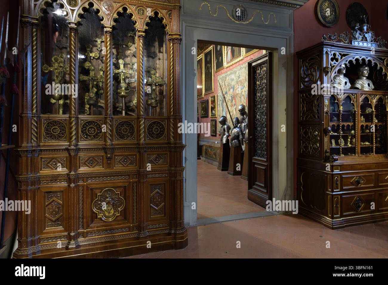 Esposizione di armadi in legno e reliquiario gotico con vista sull'adiacente galleria armature del Museo Stibbert, Firenze, Italia. Foto Stock