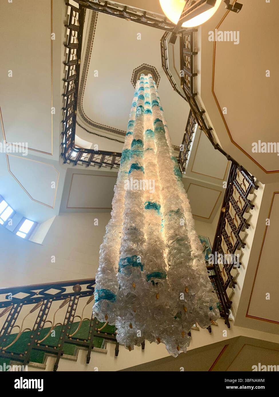 Vista dalla base della scala a chiocciola dell'Ortea Palace Hotel a Siracusa, dove eleganti opere in ferro incorniciano un arredamento d'arte moderna a cascata. Foto Stock