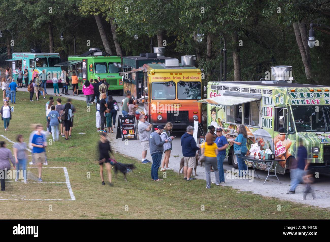 Lilburn, GA / USA - 10 ottobre 2023: Motion Blur mostra le persone che patrocinano cinque camion alimentari in un parco pubblico, il 10 ottobre 2023 a Lilburn, GA. Foto Stock