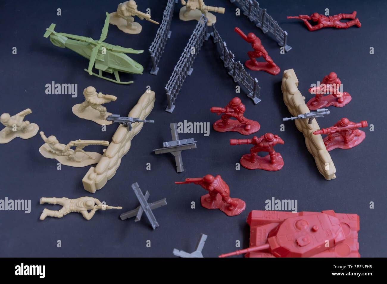 Battaglia in miniatura - concetto di aggressione militare. Figure plastiche di soldati di lati opposti sullo sfondo di fortificazioni di difesa. Concetto Foto Stock