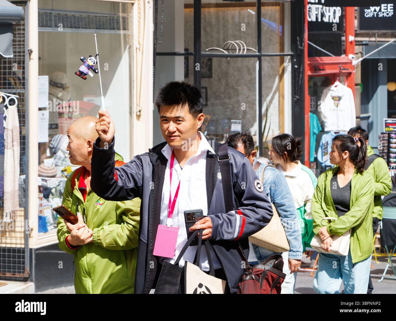 Un uomo asiatico ha una bandiera mentre guida un gruppo di turisti cinesi lungo il Royal Mile di edimburgo in scozia Foto Stock