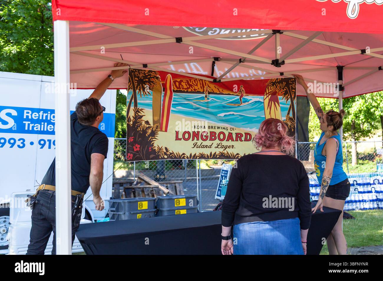 The Big Float, Portland, Oregon - 13 luglio 2019: Persone che allestiscono uno stand Kona Brewing, appeso a un banner Longboard Island Lager. Foto Stock