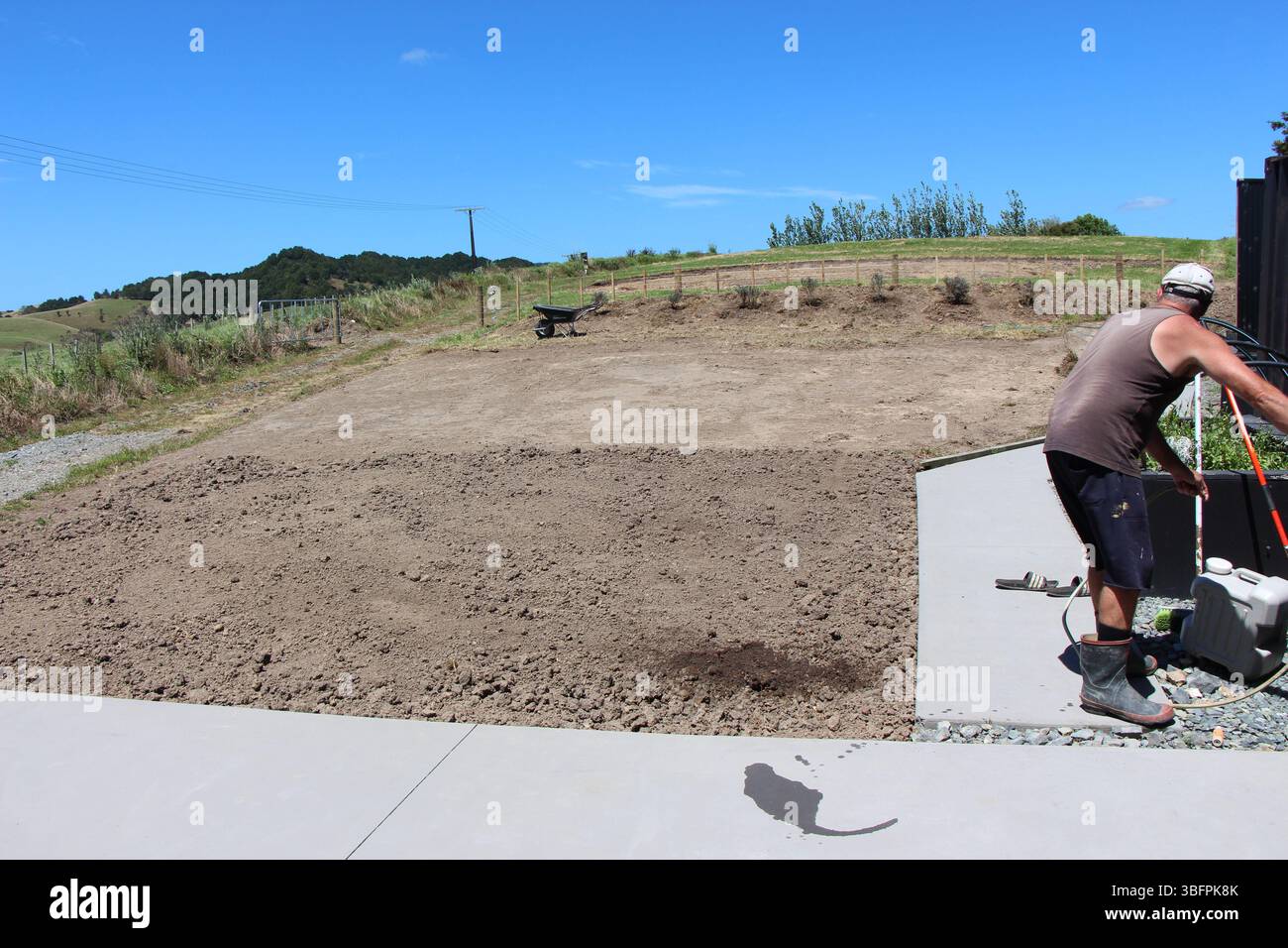 Uomo al lavoro. Preparare il terreno per piantare semi di prato, in un blocco di stile di vita rurale, Northland NZ. Foto Stock