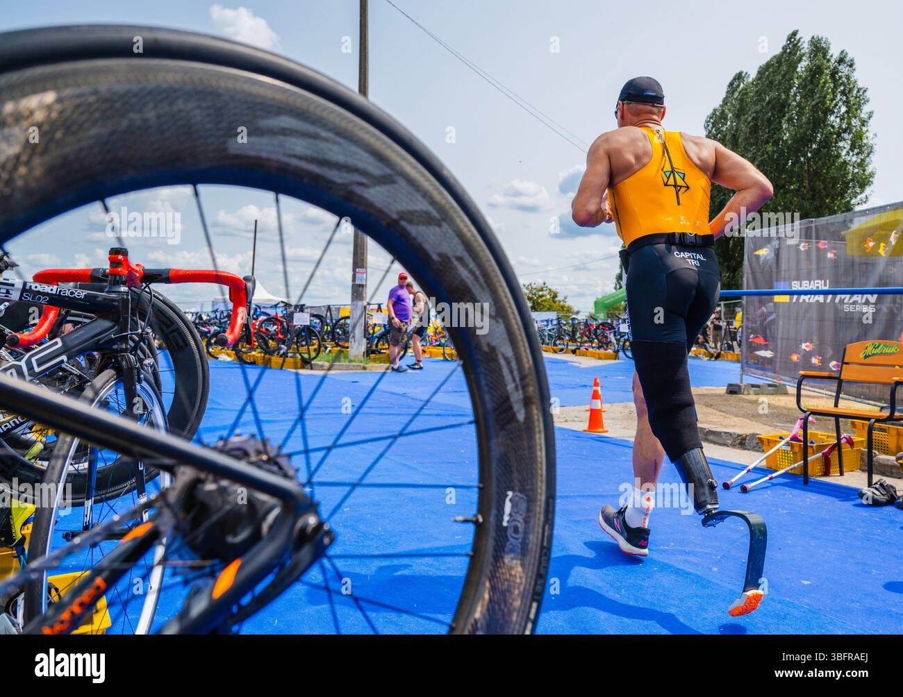 Kiev, Ucraina - 1 giugno 2025: Paratriatleta con una gamba protesica che attraversa la zona di transizione durante un triathlon, circondato da biciclette da corsa e altri atleti e funzionari credito: ARTEM HVOZDKOV/Alamy Live News Foto Stock