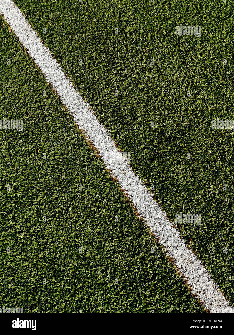 Il prato artificiale verde rigoglioso presenta una linea bianca appena verniciata che segna chiaramente il confine in preparazione di un evento sportivo imminente, Foto Stock