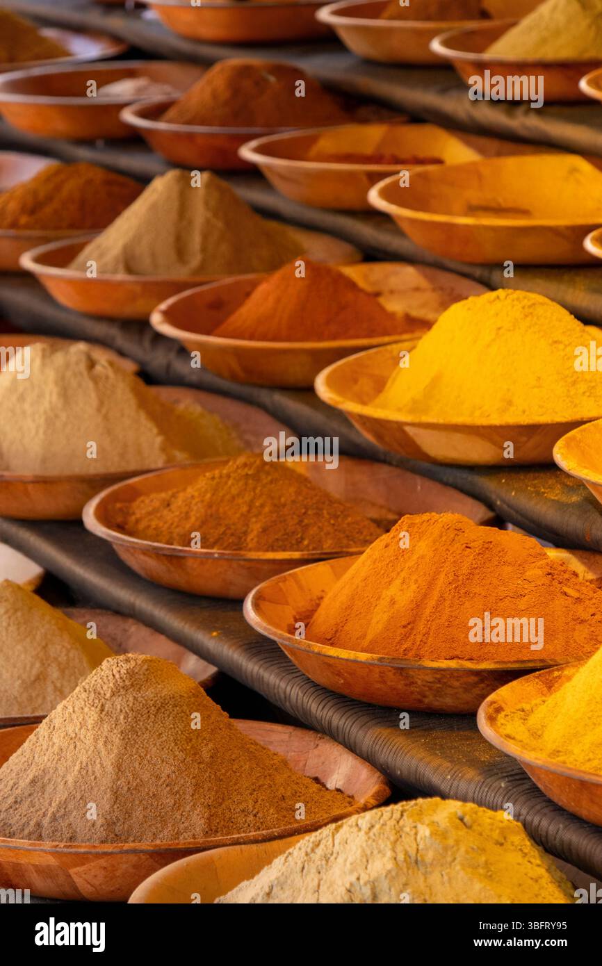 Vivace assortimento di spezie in polvere dai toni caldi, ordinate in ciotole di legno in un mercato all'aperto o in una fiera alimentare. Foto Stock