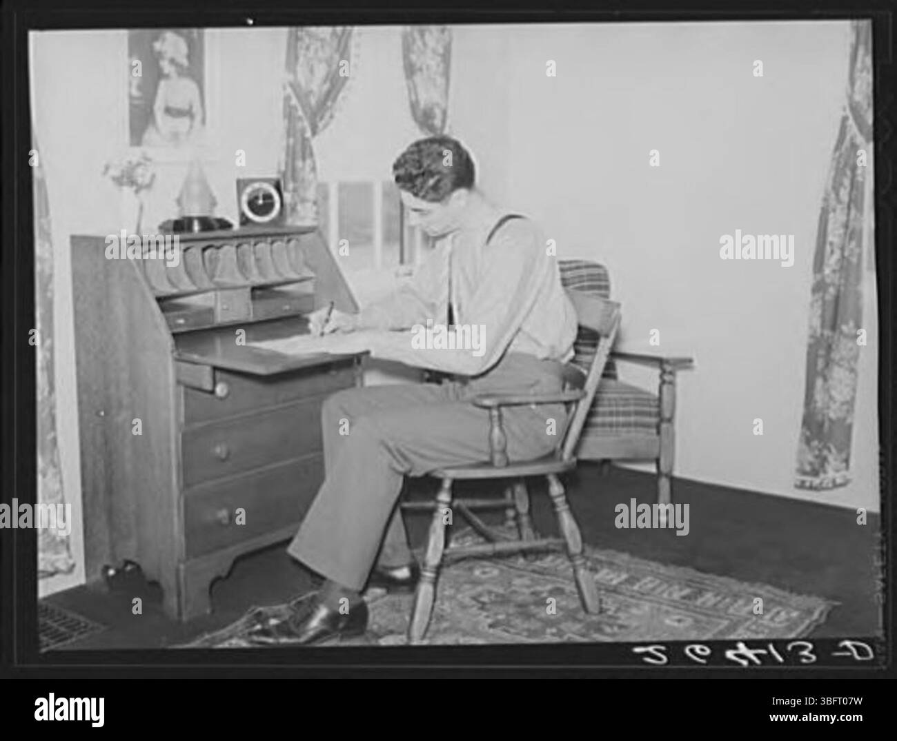 Questa immagine raffigura John Kindler, un impiegato di un hotel, all'interno della sua casa a Homesteads. La foto offre uno sguardo sulla sua vita personale e sulle sue condizioni di vita, illustrando la vita della classe operaia durante il suo tempo. Foto Stock