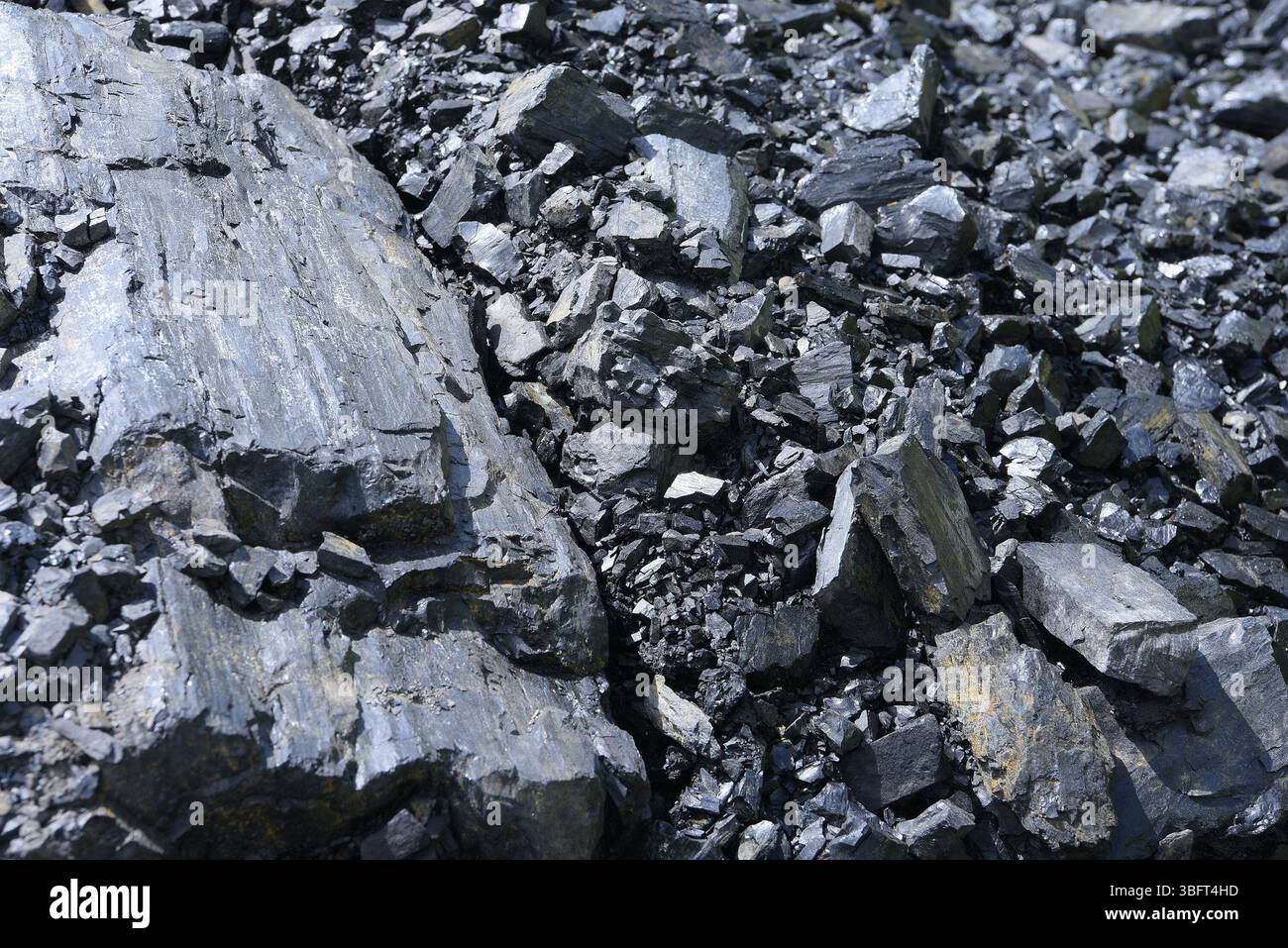 Immagine dettagliata dettagliata di frammenti di carbone grezzo e rocce nere lucide, generalmente presenti in siti minerari a cielo aperto o sotterranei. Foto Stock