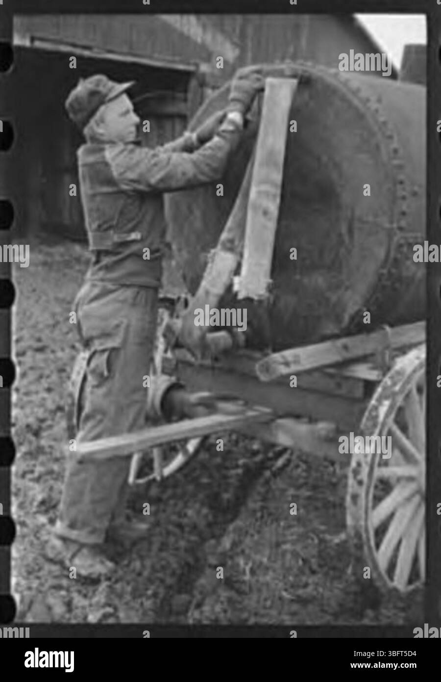 Due agricoltori si trovano vicino a un grande serbatoio d'acqua metallico utilizzato per immagazzinare e distribuire acqua, probabilmente per scopi agricoli. Foto Stock