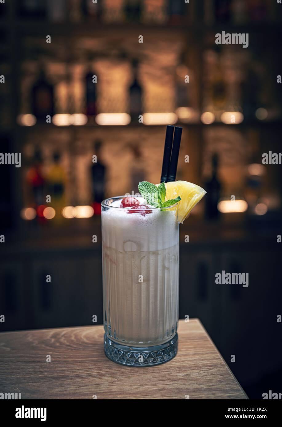 Cremoso e tropicale pina colada cocktail guarnito con zeppa di ananas e rametto di menta si siede in un bar, pronto per essere gustato Foto Stock Cremoso e tropicale pina colada cocktail guarnito con zeppa di ananas e rametto di menta si siede in un bar, pronto per essere gustato Foto Stock
