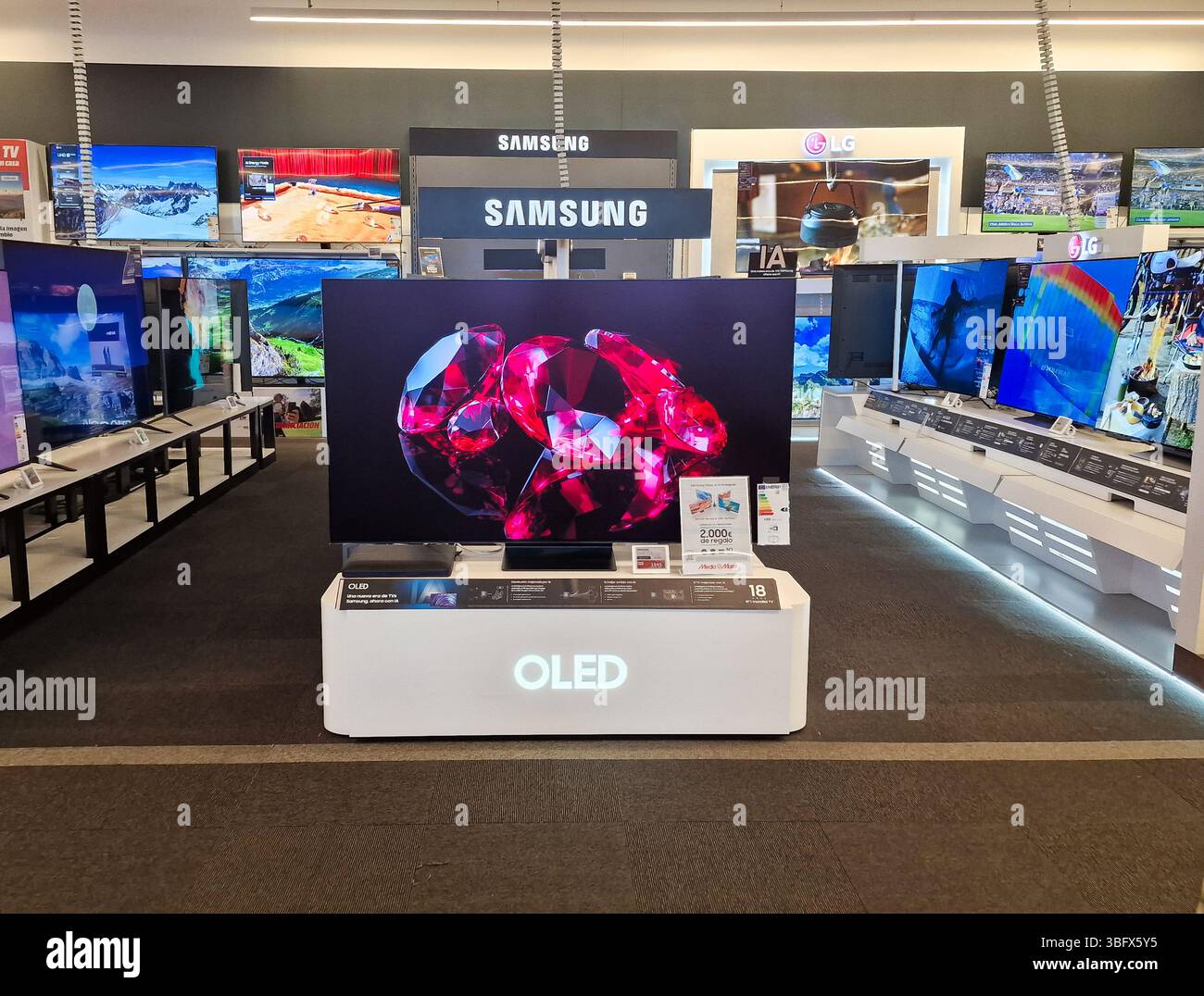 Almeria, Spagna - 2 giugno 2025: TV Samsung OLED in evidenza nel negozio di elettronica, circondato da altri televisori che mostrano colori vivaci e Foto Stock