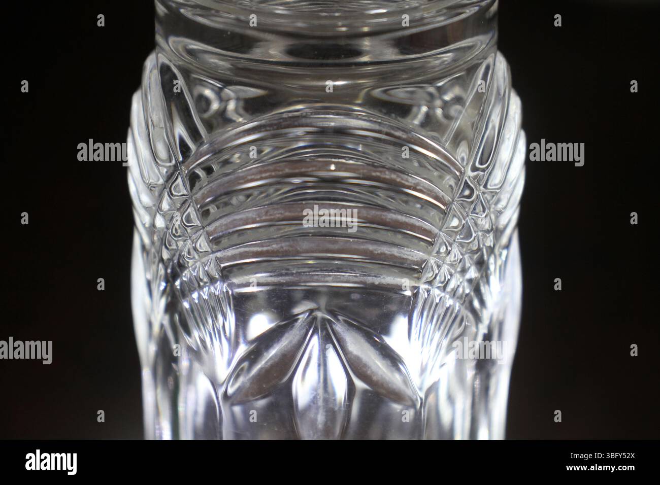 Un bicchiere decorativo in vetro trasparente o cristallo. Il vetro presenta motivi e incisioni intricati e simmetrici, comprese le scanalature verticali. Foto Stock