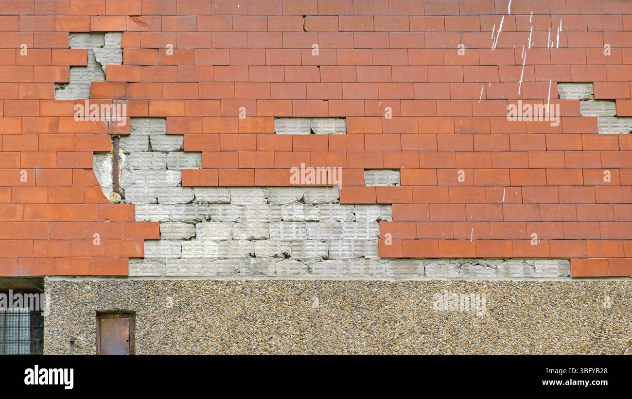 Muro rotto stacca i danni alla casa delle piastrelle in ceramica arancione Foto Stock