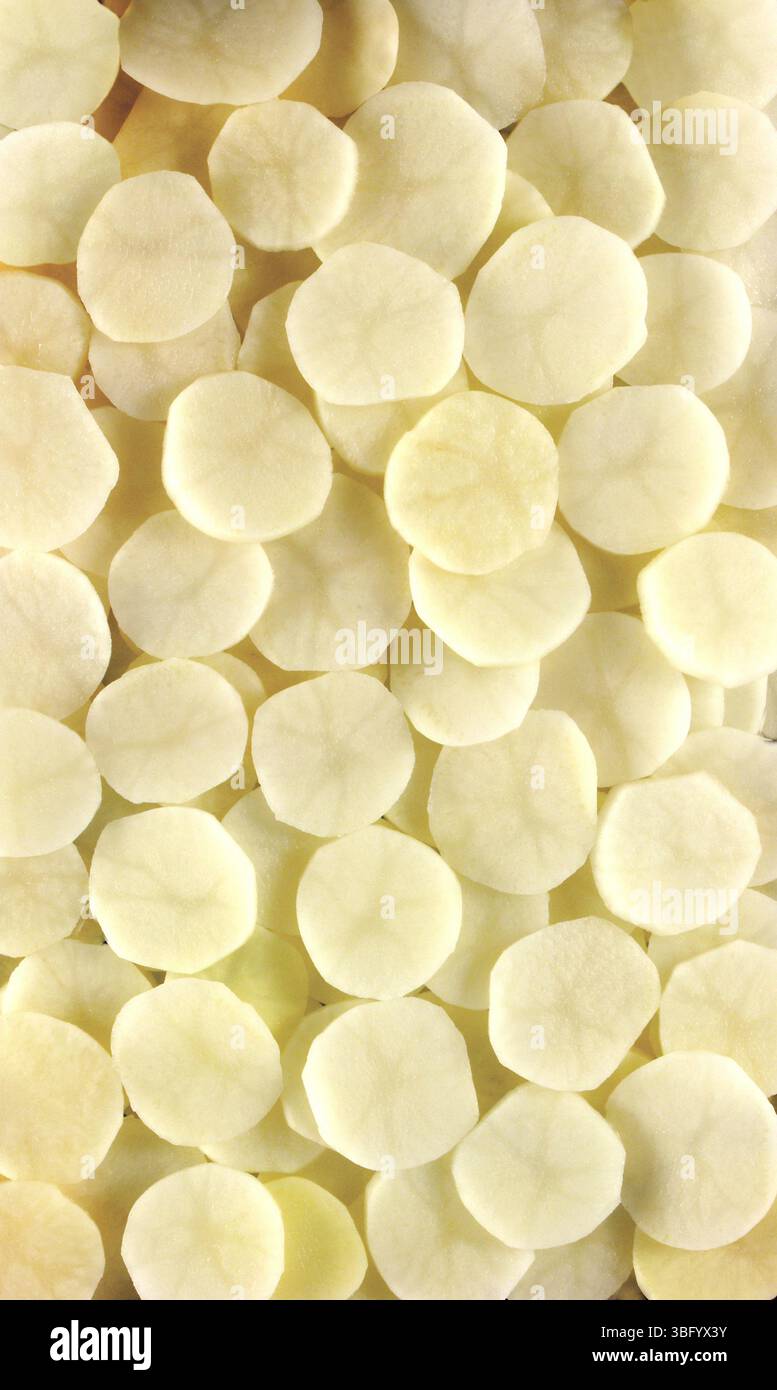 Patate a fette che riempiono la cornice creando uno sfondo alimentare Foto Stock