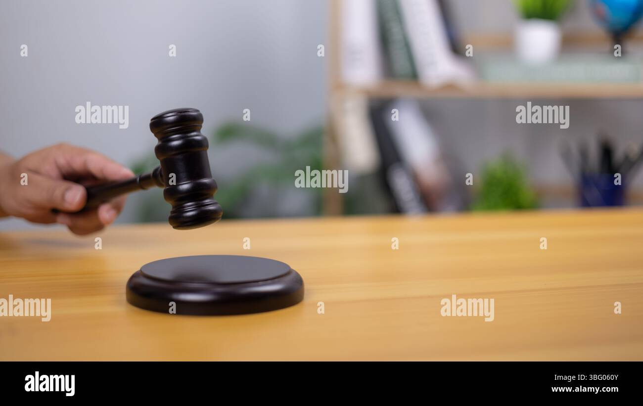 La mano di un giudice regge un martelletto di legno, che simboleggia la giustizia, la legge e il processo decisionale. L'immagine riflette l'autorità, i procedimenti giudiziari, i contesti giudiziari, per Foto Stock