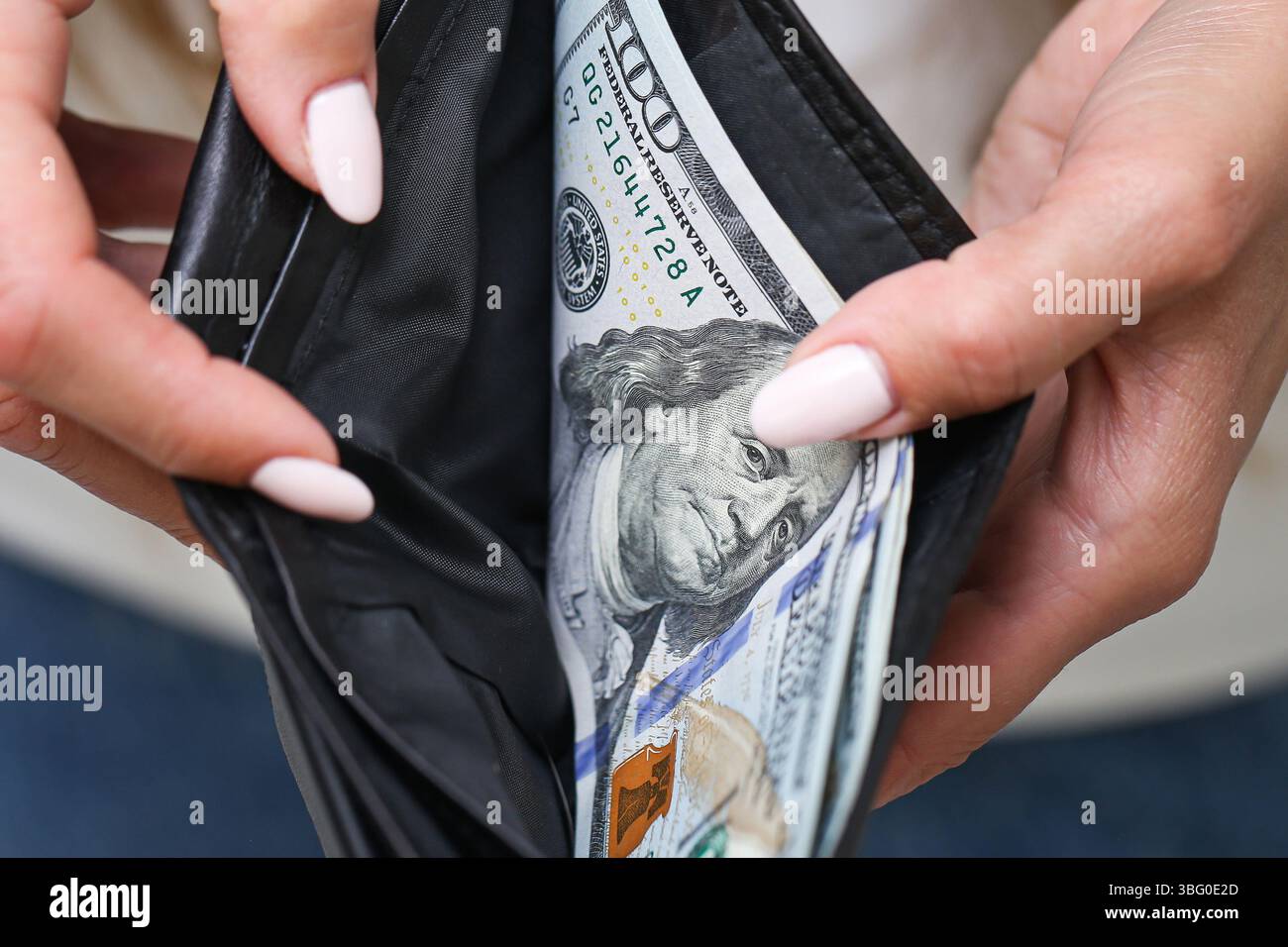 Donna che tiene il portafoglio con i dollari. Borsa nera in pelle piena di contanti. Finanza personale e denaro. Primo piano di mani e bollette. Valuta americana. Foto Stock