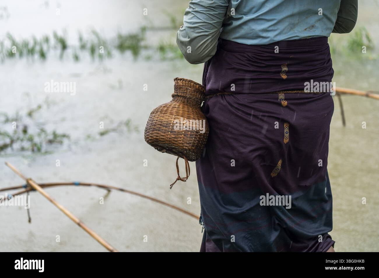 Una donna tribale che pesca durante una forte pioggia a Golapara, in India, il 31 maggio 2025 Foto Stock