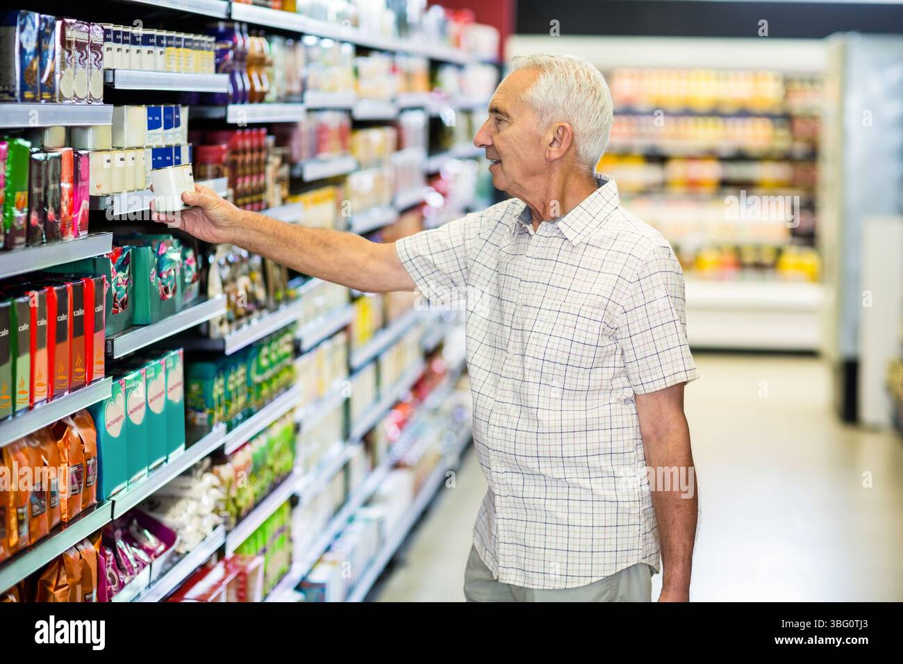 Il negoziante maschio senior afferra il cartone dalla scaffalatura del supermercato vicino all'esposizione del frigorifero, spazio per le copie Foto Stock