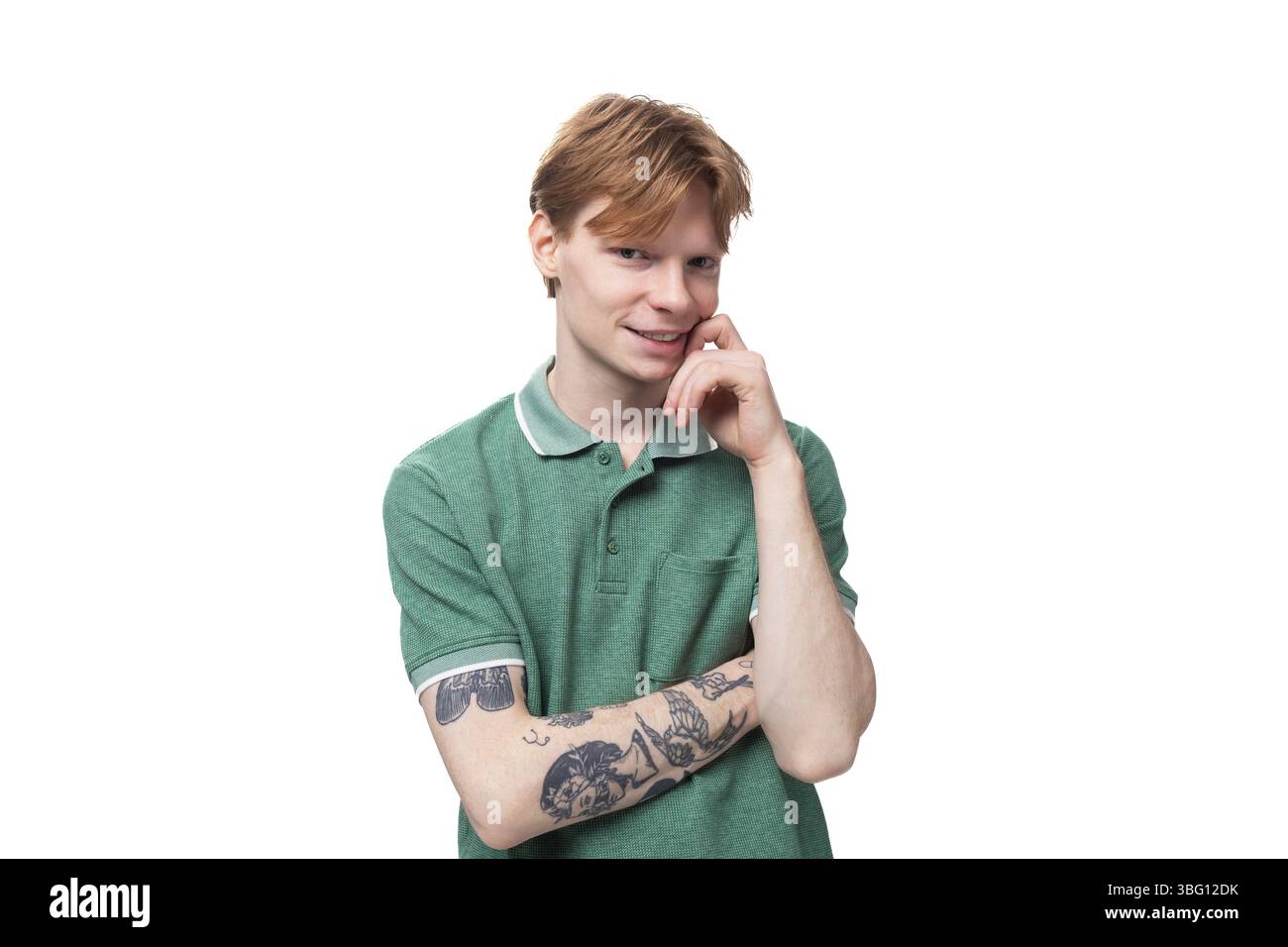 Un giovane europeo con i capelli rossi e un'acconciatura elegante è vestito con una t-shirt verde estiva con colletto Foto Stock