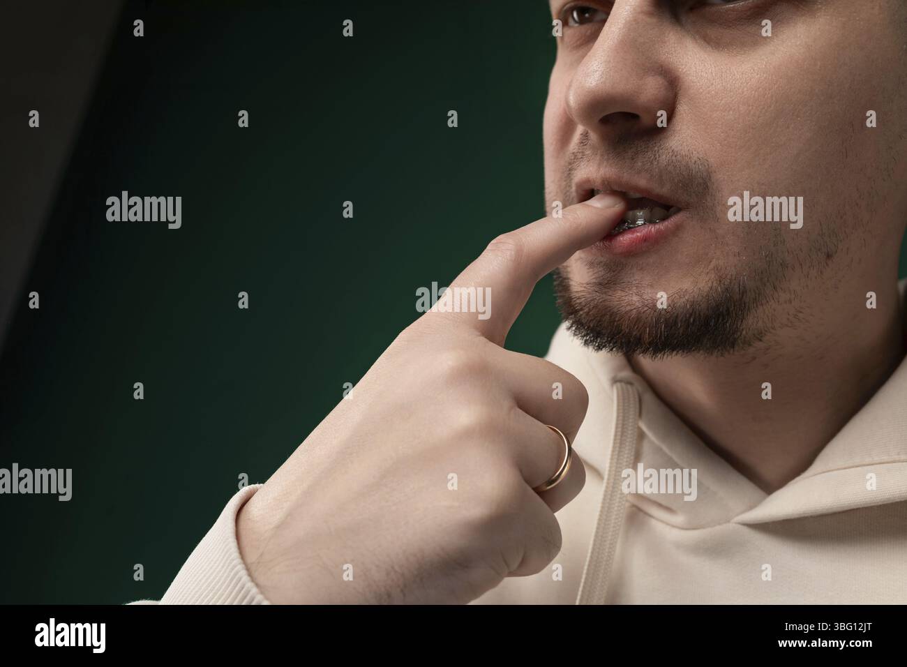 Un uomo sta tenendo il dito indice verso il naso, sembra essere in profonda riflessione o contemplazione. La sua espressione facciale è concentrata, suggerendo che è co Foto Stock