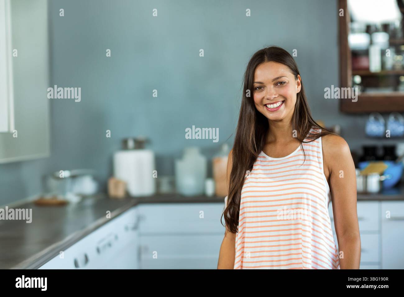 Donna alla fine degli anni '20 in piedi al bancone della cucina di casa vicino al tagliere e agli utensili Foto Stock