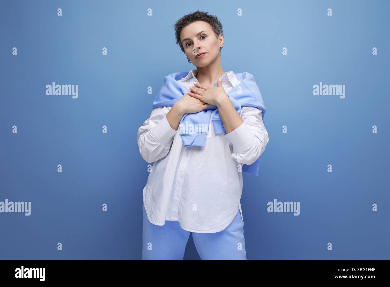 Sconvolge la giovane donna dai capelli scuri con i capelli attaccati in una camicia bianca Foto Stock