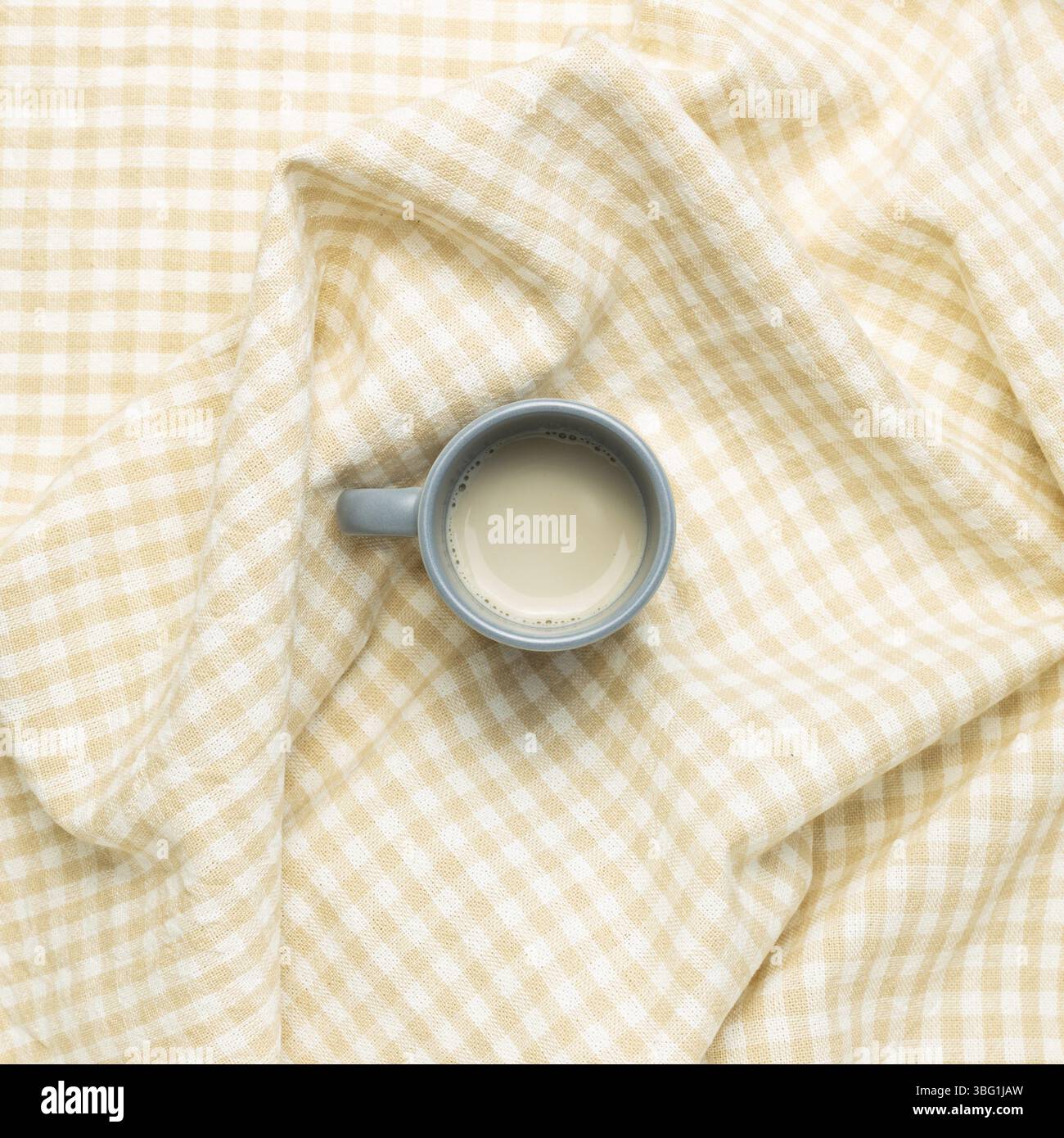 Tazza di tè al latte su fondo in tessuto beige crumpled check pattern. Vista dall'alto Foto Stock