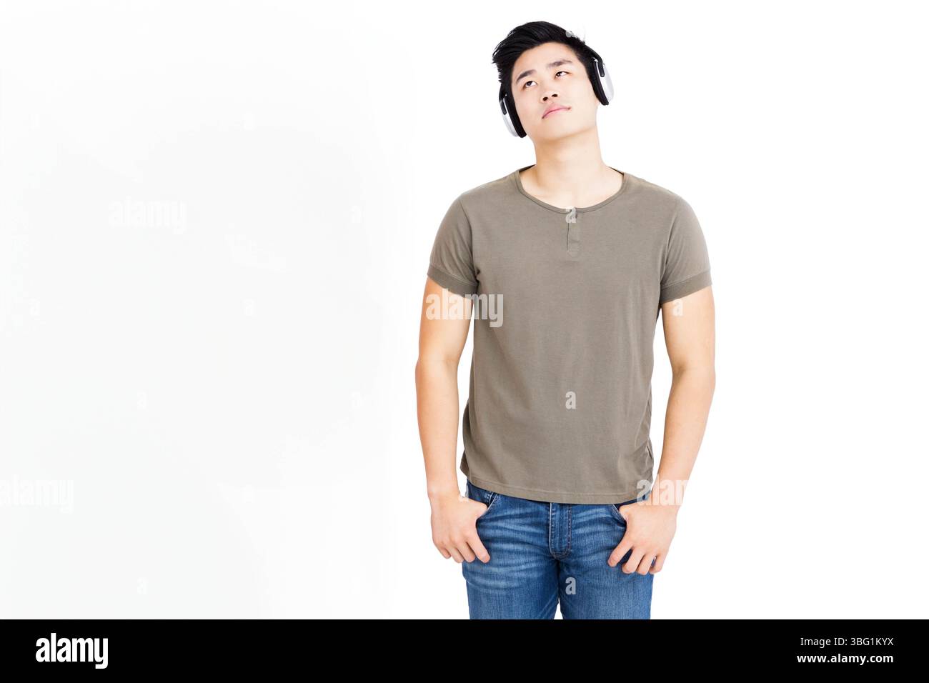 Uomo asiatico in piedi in studio su sfondo bianco con cuffie e abbigliamento casual, spazio copia Foto Stock