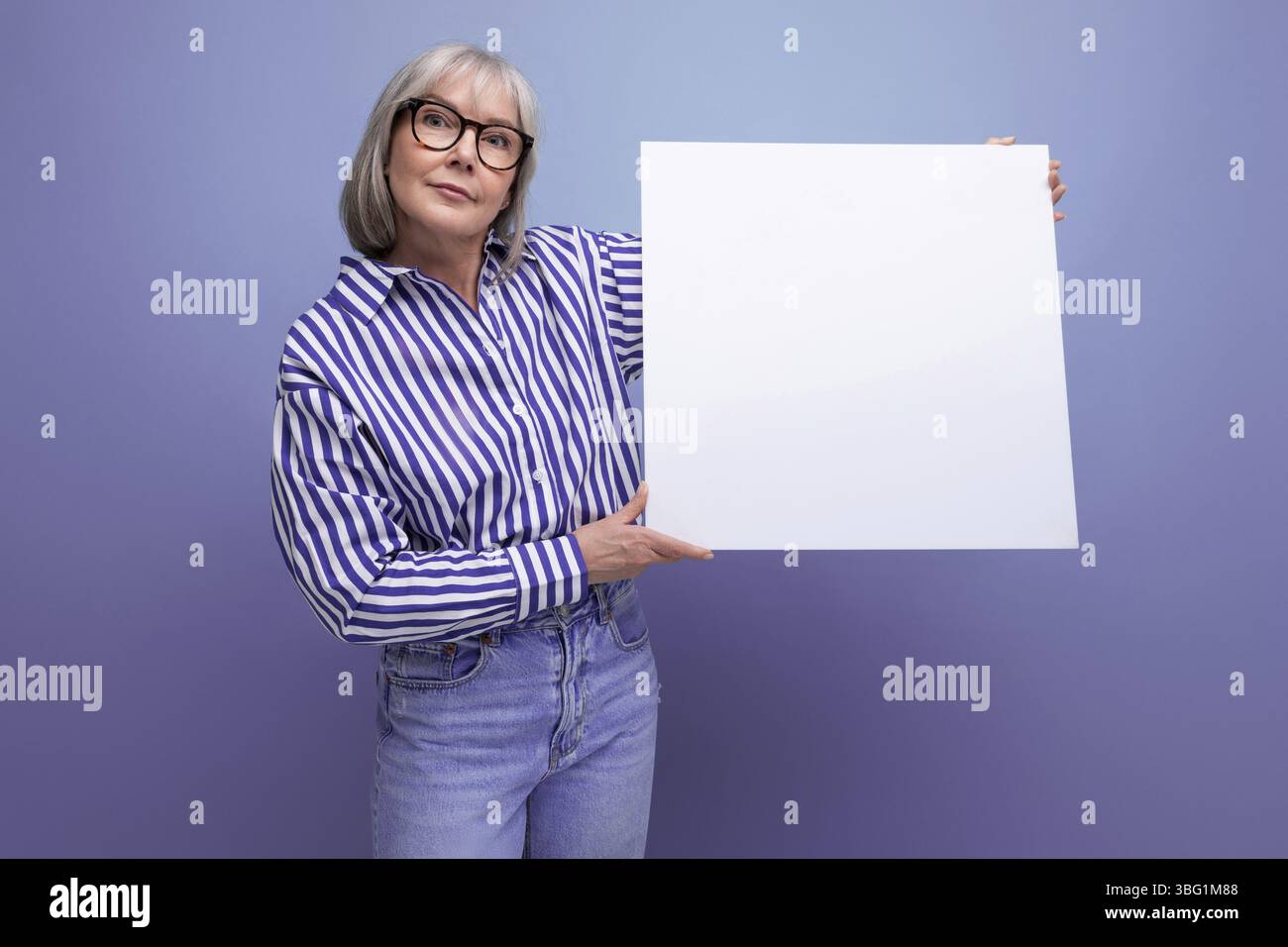 60er jahre mittelalter geschaeftsfrau zeigt blanko-affissioni mit mockup auf hellen studio hintergrund Foto Stock