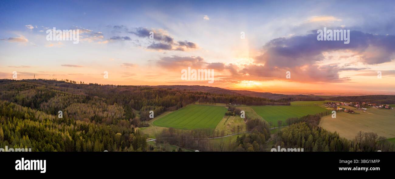 Vista aerea del tramonto estivo su campi verdi e foreste, tramonto al tramonto e belle nuvole Foto Stock