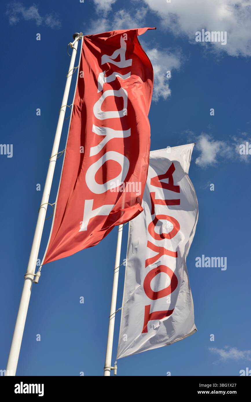 Bandiere Toyota che sventolano contro il cielo blu presso la concessionaria Foto Stock