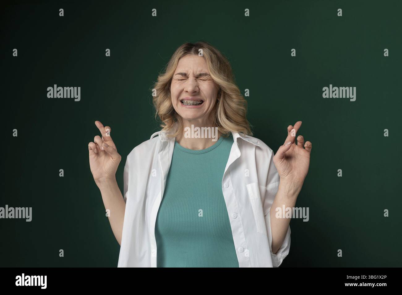 Una donna in piedi con gli occhi chiusi, entrambe le mani alzate in aria. Sembra pacifica e riflettente, come in profonda concentrazione o meditazione Foto Stock