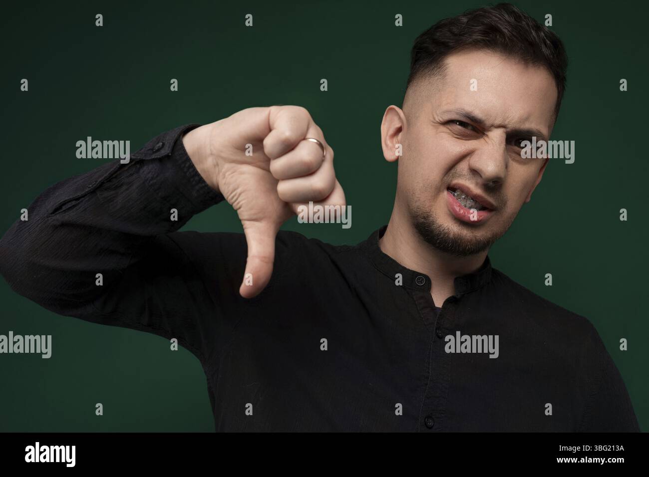 Un uomo con la mano alzata, che fa un segno con il pollice per esprimere approvazione e positività. Il gesto mostra l'accordo, il sostegno e l'incoraggiamento Foto Stock