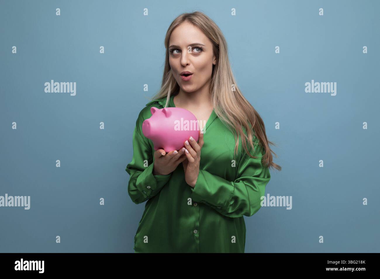 Europaeisch ueberrascht stilvolle bionda maedchen mit salvadanaio auf blauem hintergrund Foto Stock