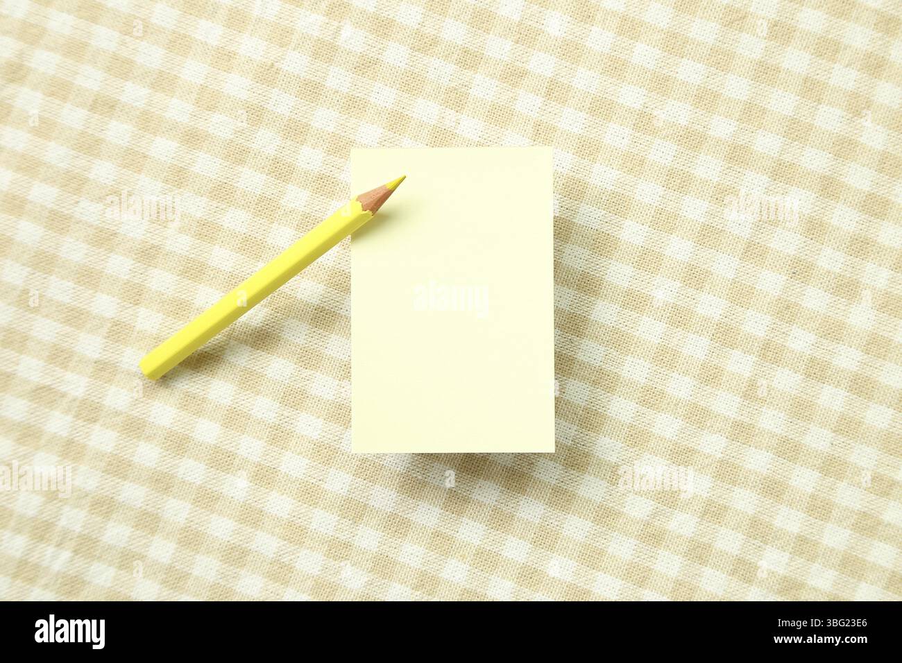 Giallo nota memo pad e colorato in giallo matita su beige modello di controllo sfondo di tessuto Foto Stock