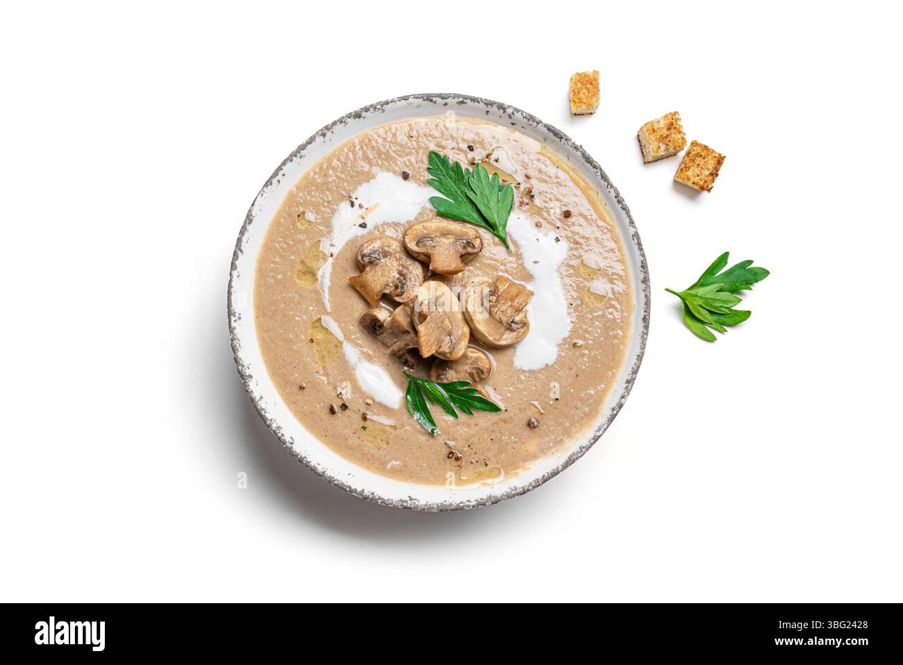 Zuppa di crema di funghi in un recipiente con crostini e prezzemolo isolati su sfondo di legno bianco, vista dall'alto, elemento di design. Fungo champignon stagionale autunnale Foto Stock