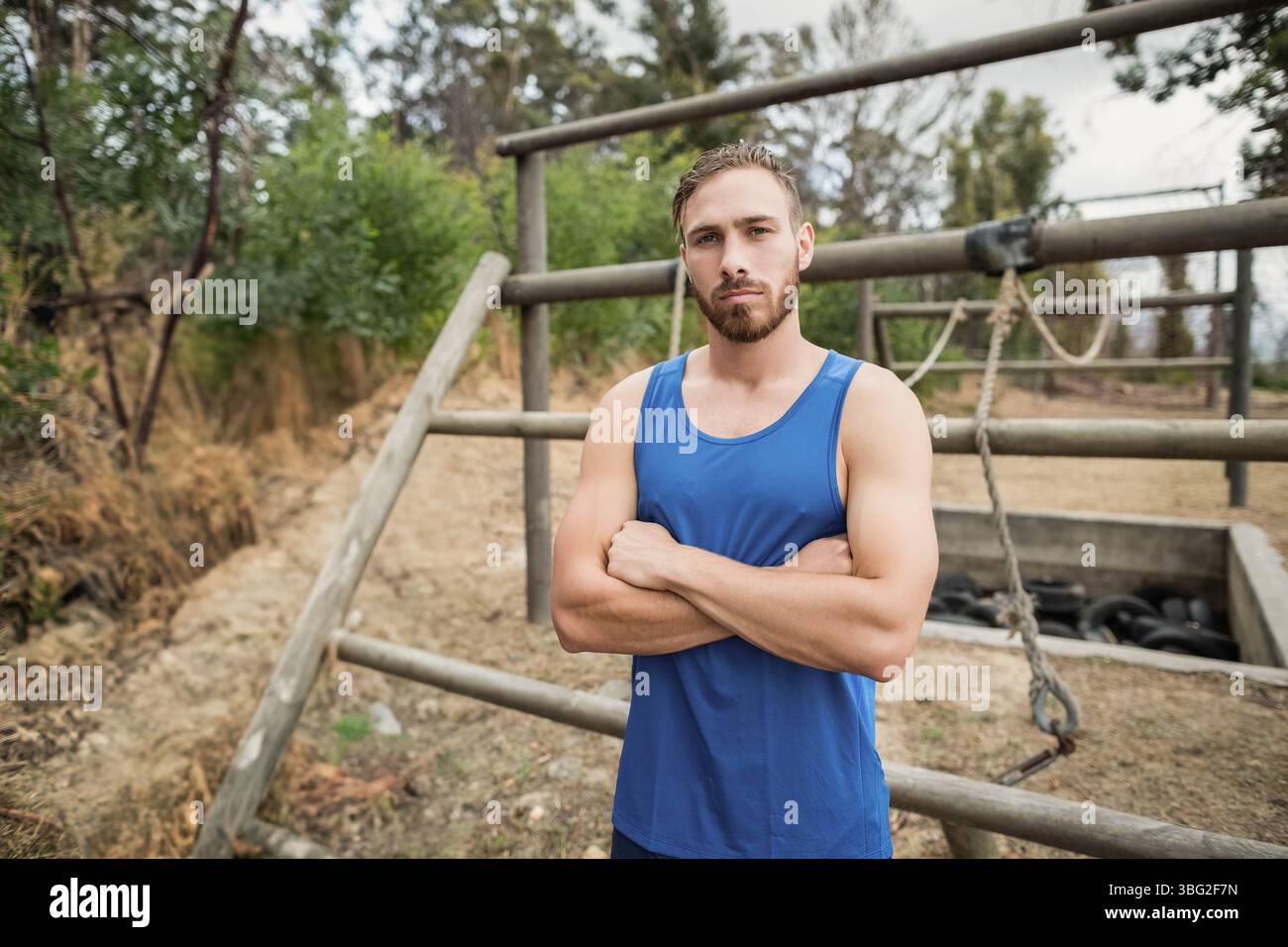 Indossare abbigliamento sportivo su un campo di allenamento di fronte ad ostacoli con funi sospese e fossa per pneumatici Foto Stock