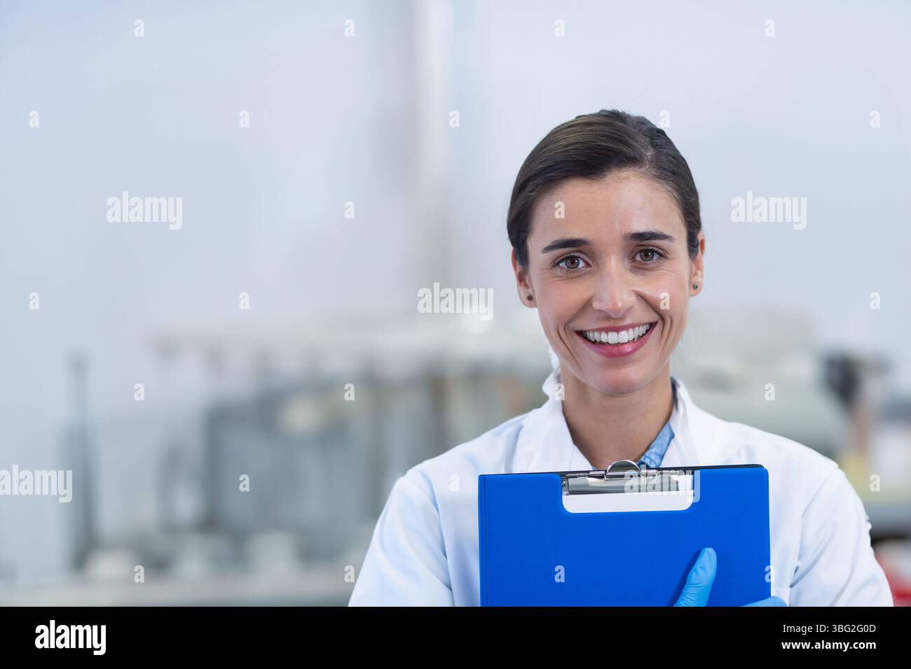 Tecnico di laboratorio donna che indossa un camice da laboratorio e guanti blu che tengono gli appunti in laboratorio, spazio di copia Foto Stock